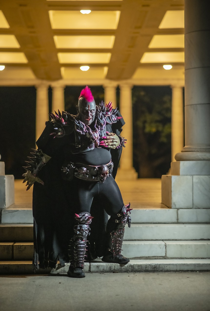 man in zombie facepaint with fake blood has a pink mohawk and is wearing spiky armor