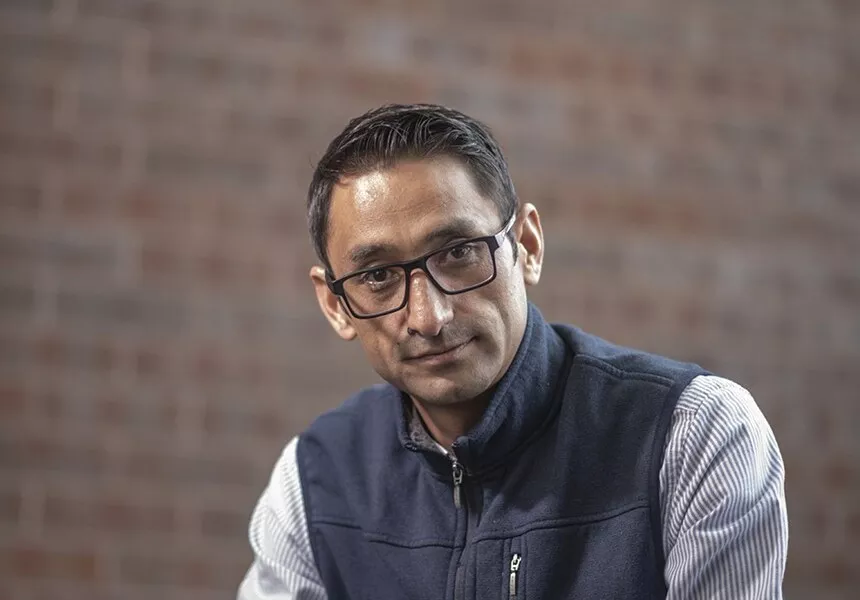 man in vest, glasses, posing against wall