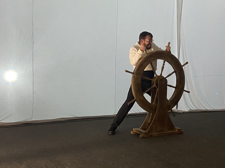 man gripping onto a ship steering wheel