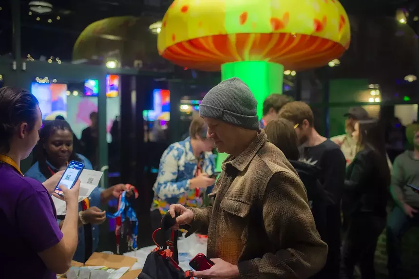 A man in front of a giant mushroom at the Denver Psychedelic Cup