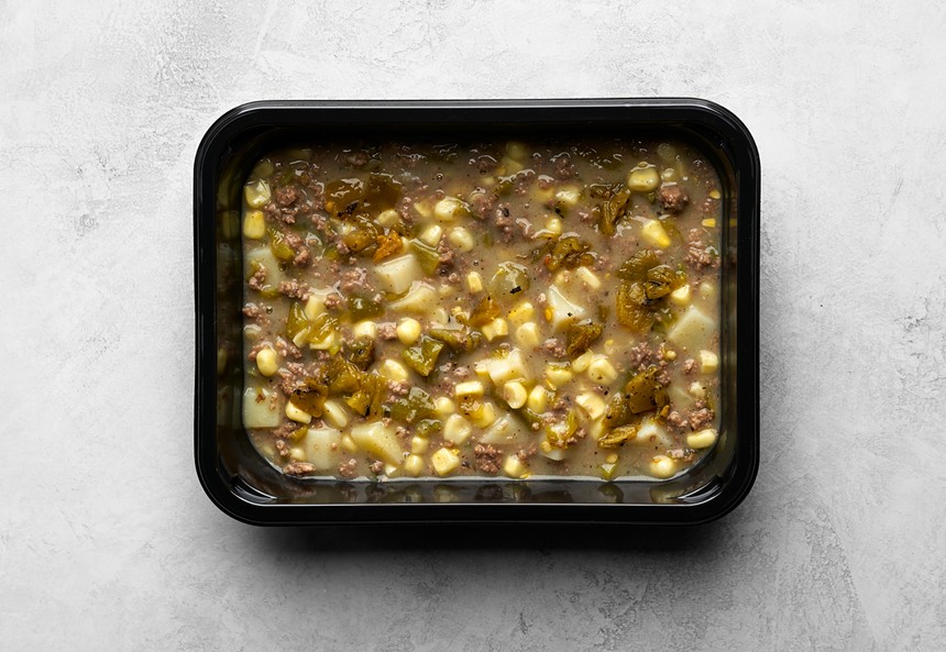 black container with green chili stew on white table