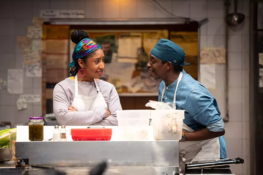 two cooks speaking to each other in a kitchen