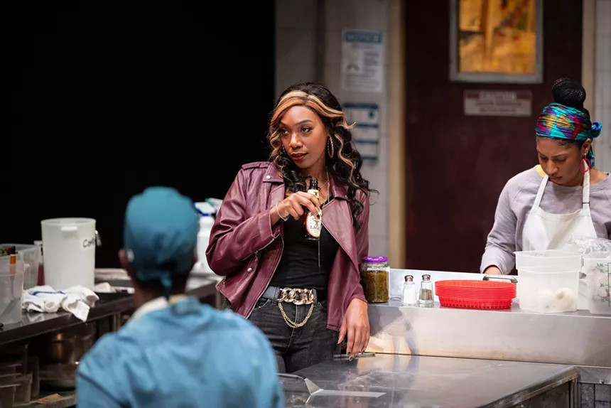 a woman in a purple leather jacket looks sassily at a cook.