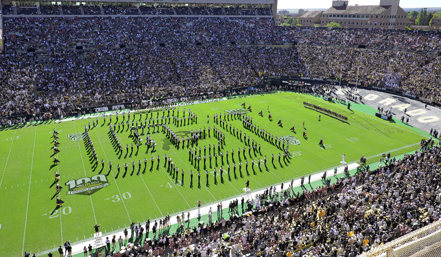 Using their bodies, people form a large "C-U" on a green field.