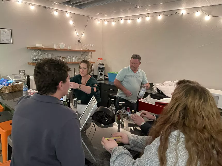 two people behind a bar and two people ordering