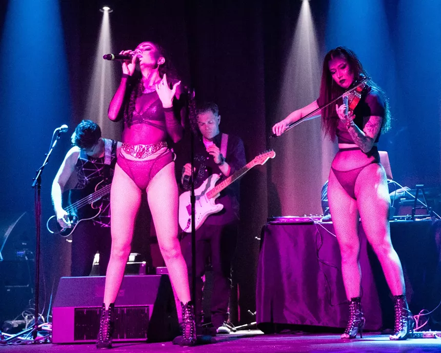 woman singing on stage while another plays violin
