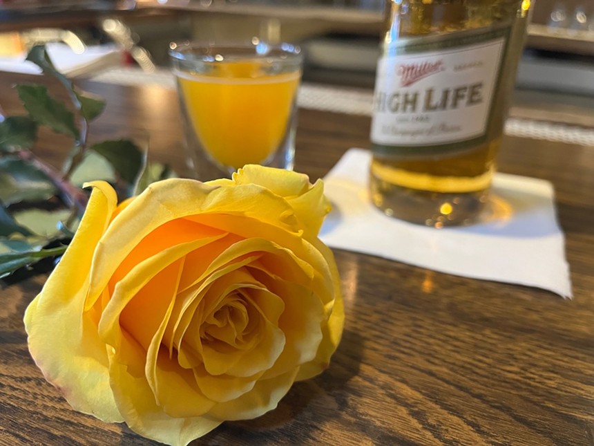 a yellow rose in front of a beer and a shot