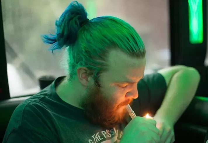 A man with a hair bun smokes weed
