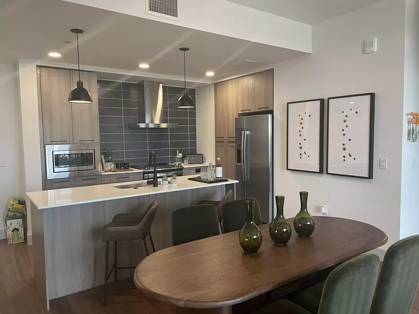 A kitchen with stainless steel appliances and pendant lights over an island.