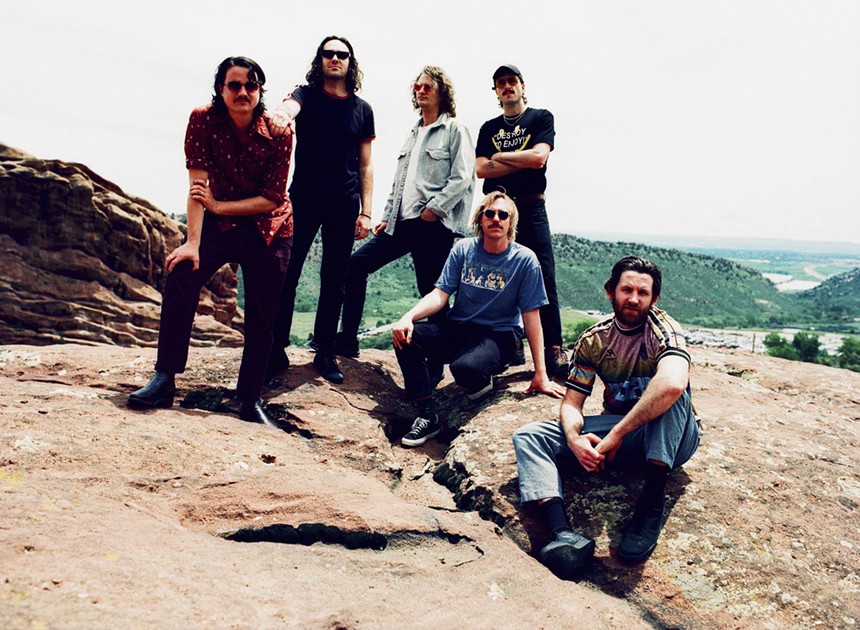 six men pose on rocks
