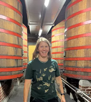 Person in green shirt stands with barrels