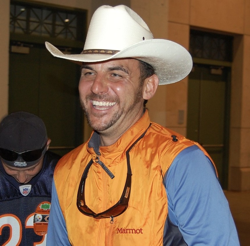a man in an orange vest and cowboy hat