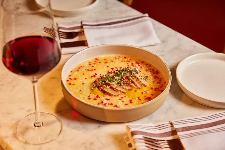 slices of fish on a plate next to a glass of wine