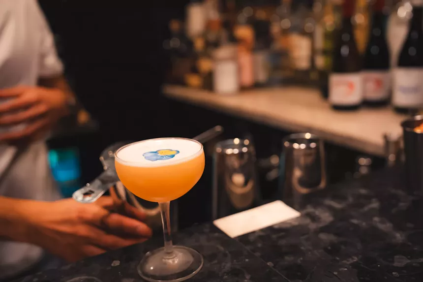a cocktail in a glass with a flower on top