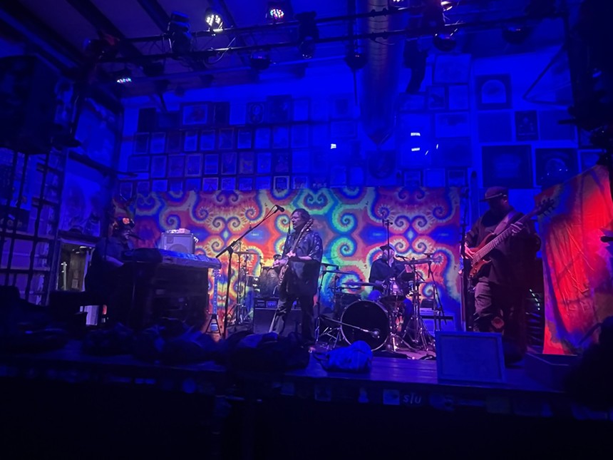 band playing on stage with psychedelic tapestry in the background
