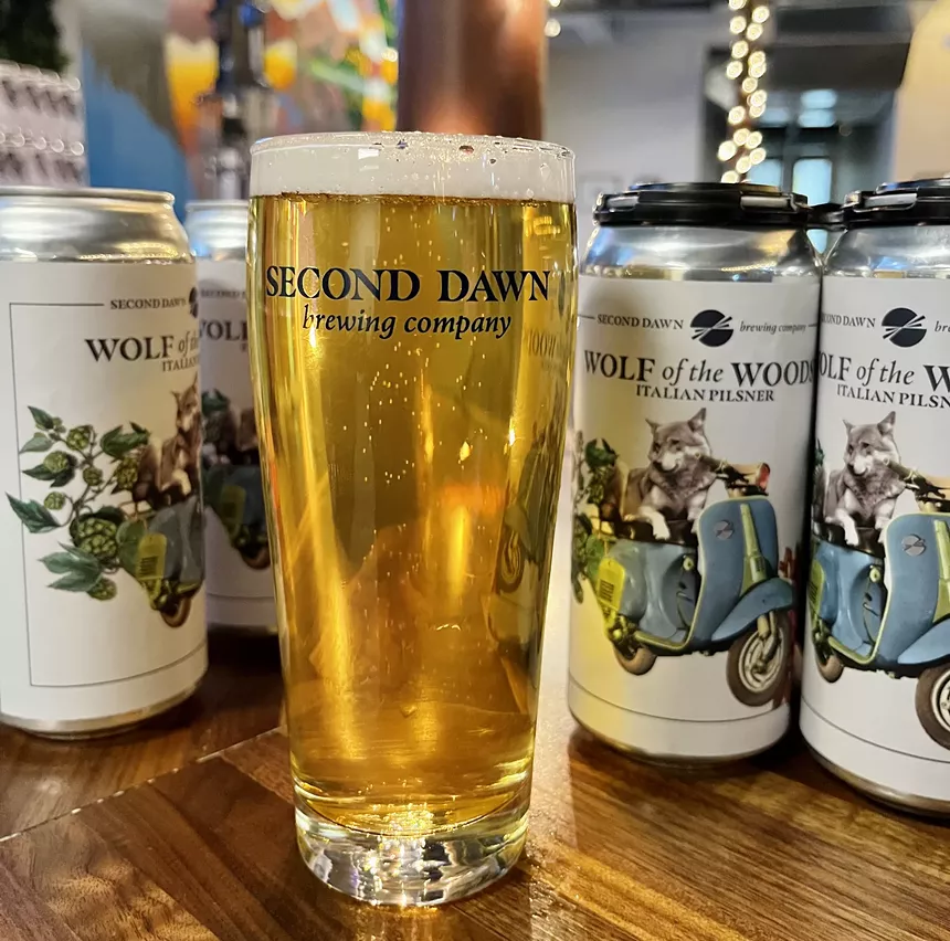 glass of beer with cans in the background.