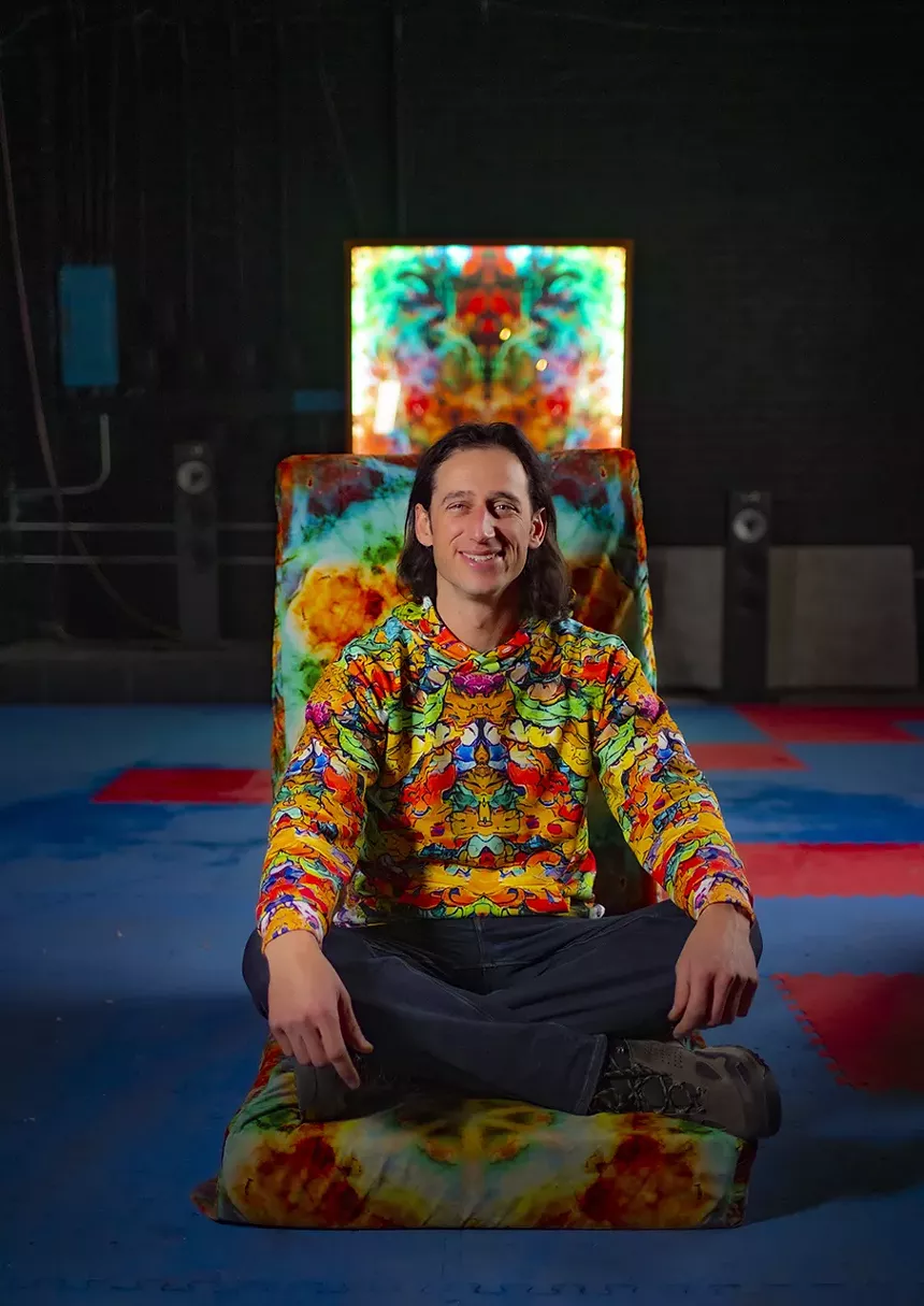 man smiles in psychedelic sweatshirt