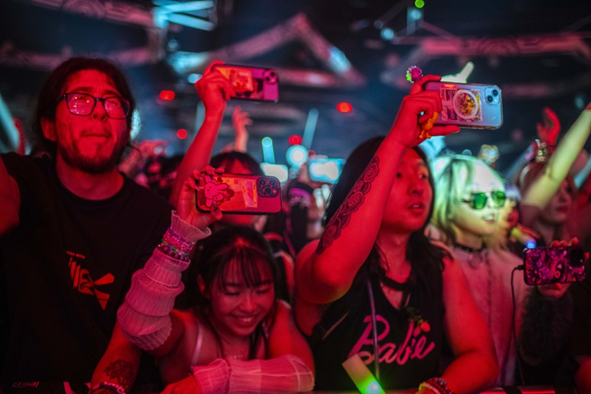 people holding up their phones at a rave