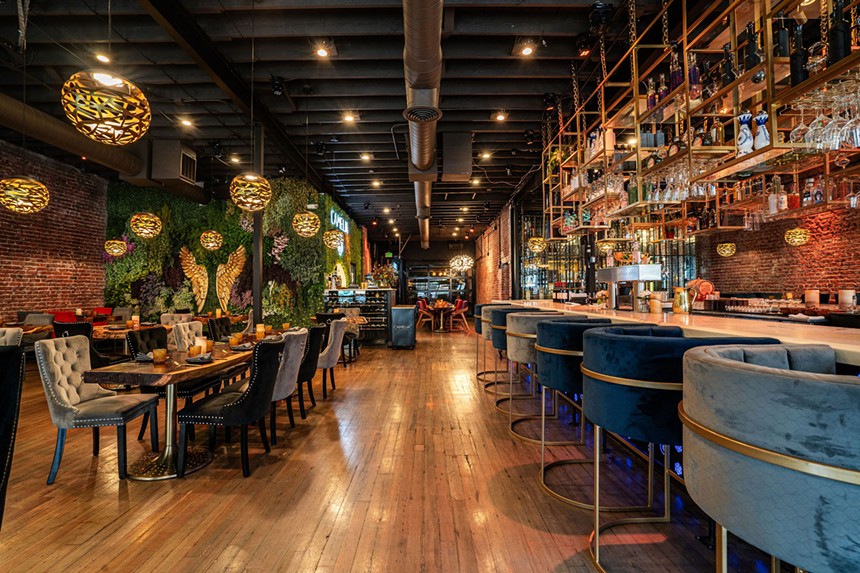 interior of a restaurant with a bar and a wall covered in plants