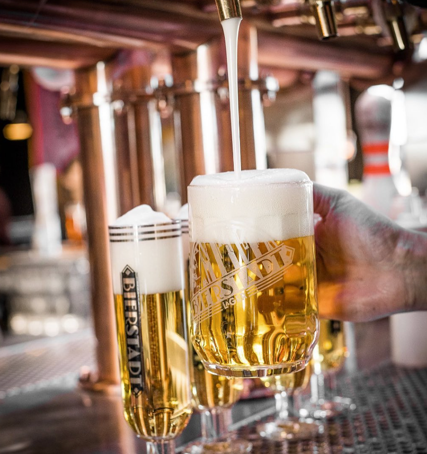 Pale lager beer with foam being poured at a bar.