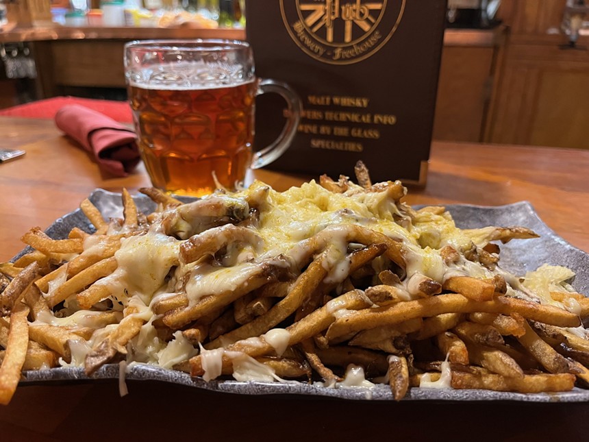 fries topped with cheese in front of a mug of beer