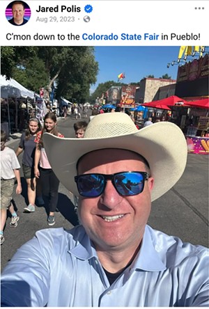 Governor Jared Polis takes a selfie in a cowboy hat.