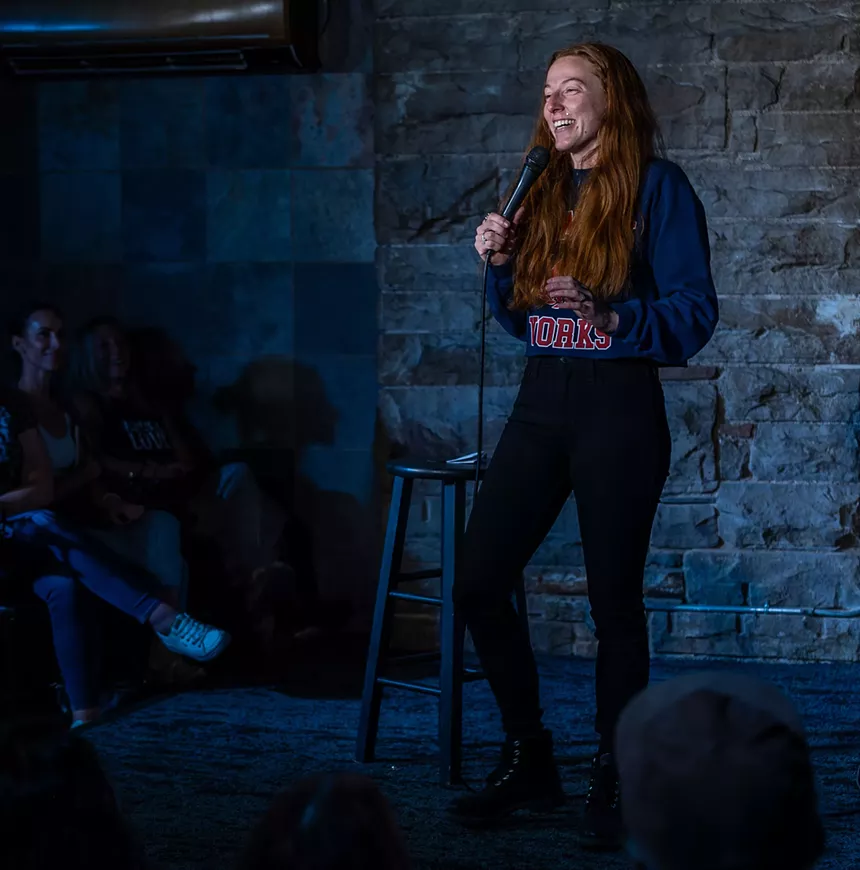 woman with red hair standing on stage with a microphone