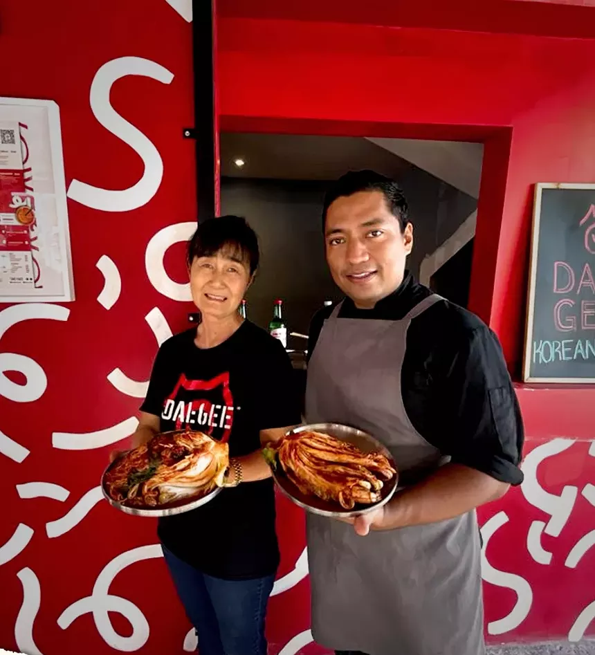 two people holding plates of kimchi