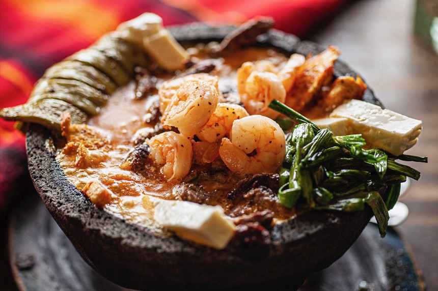 a molcajete filled with shrimp, steak, cheese and vegetables