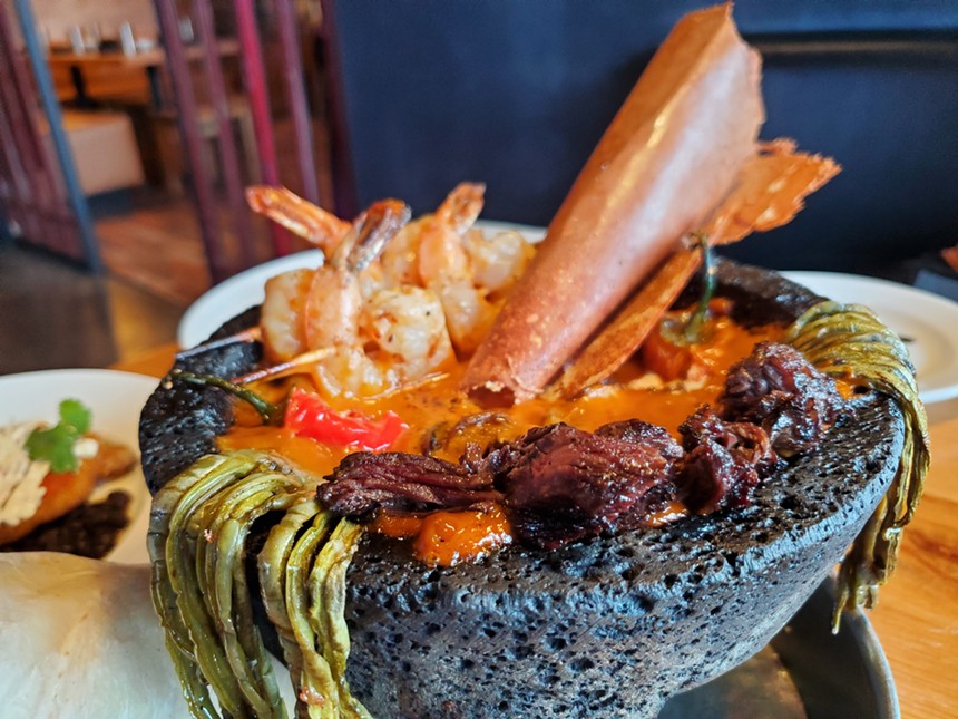 a molcajete filled with steak, shrimp and cactus