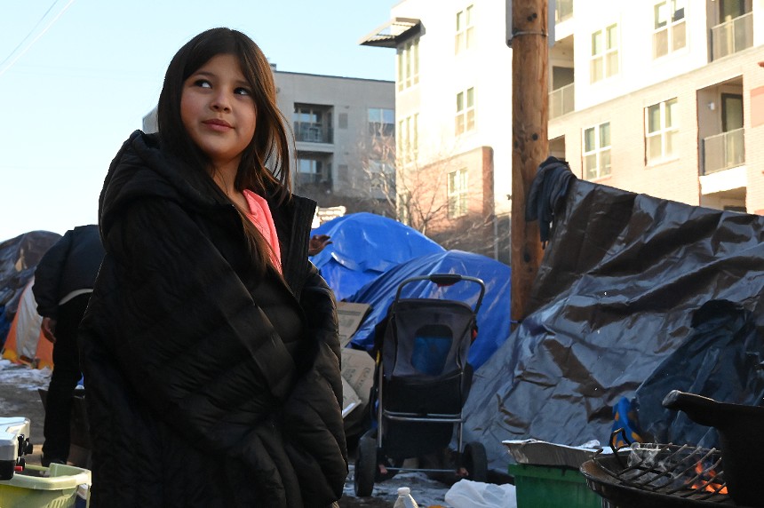 Eight-year-old Aranza Delgado stands by the tent on West 27th Avenue, where she lives with her mom.