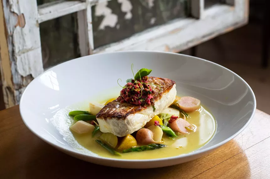 a piece of seared fish on a plate over vegetables