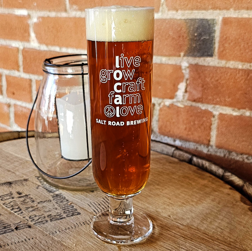 Amber colored beer in a glass on a barrel table.