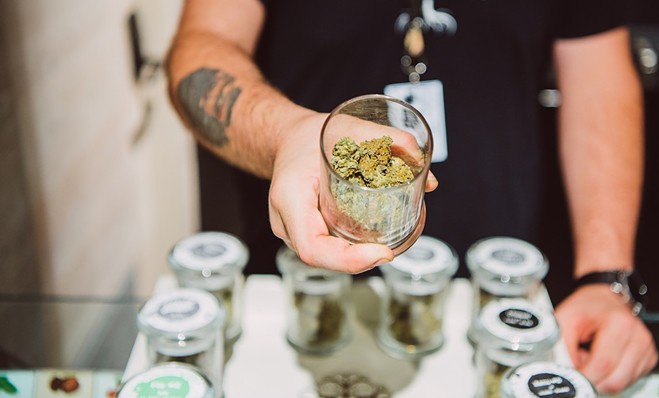A budtender displays jars of marijuana flower at a Colorado dispensary