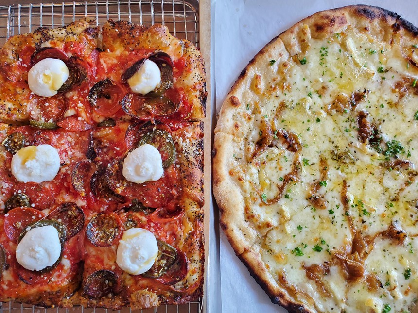 a rectangular pizza with ricotta on top next to a round white pizza