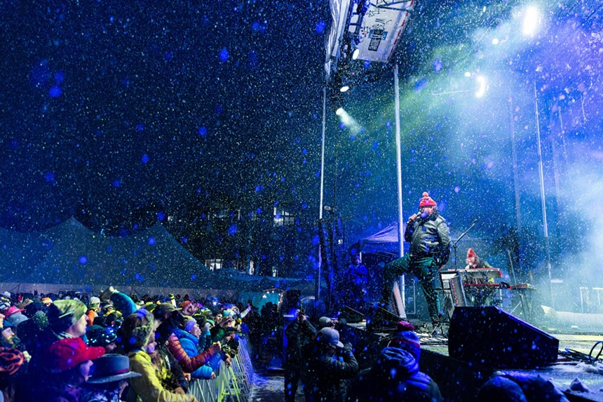 man singing on stage while snow falls
