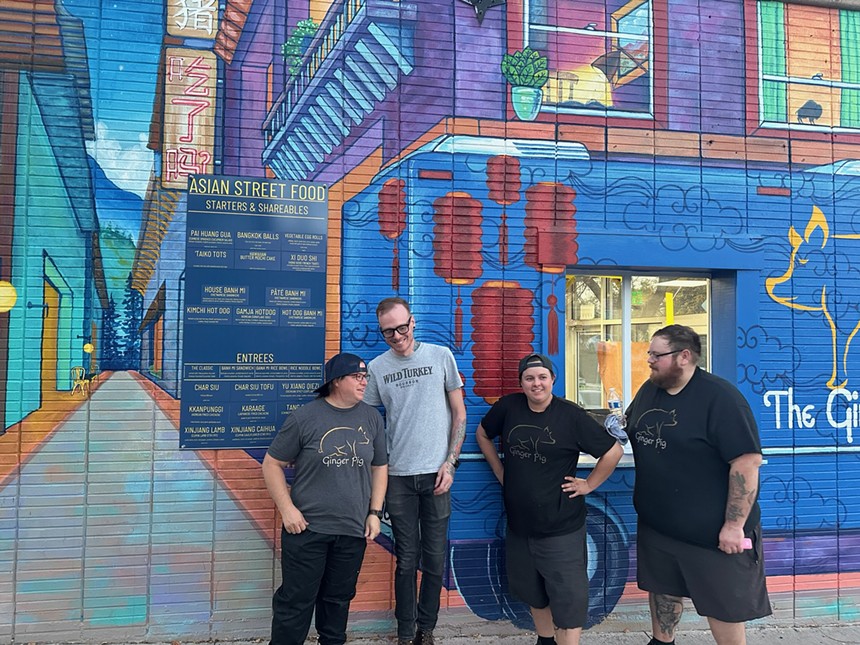 four people standing in front of a mural