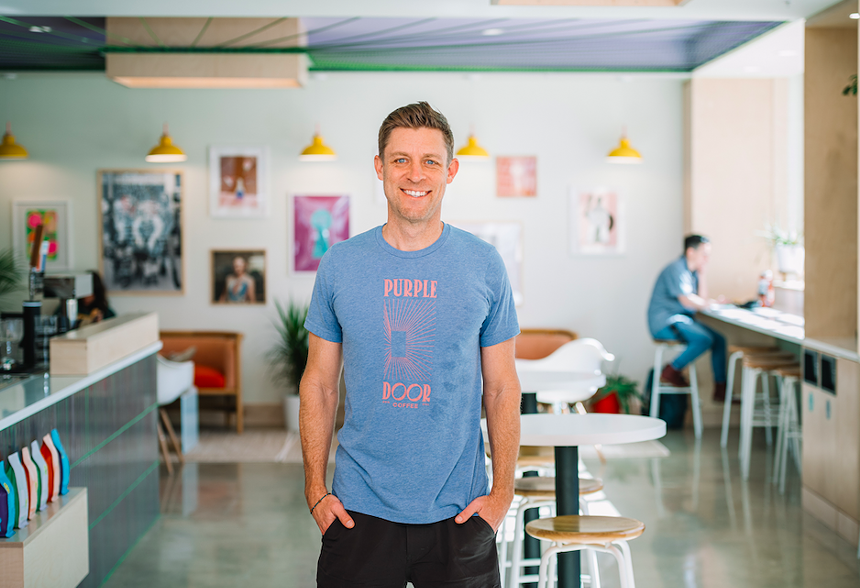 a man in a blue t-shirt standing in a coffee shop