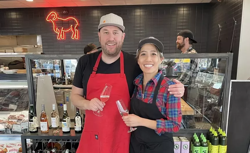 a man in a red apron posing with a woman in a black apron