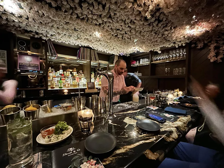 A Death & Co bartender mixing cocktails behind the bar