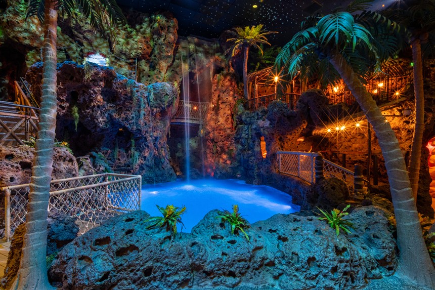an indoor pool surrounded by cliffs and palm trees