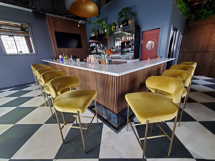 yellow velvet chairs lined up in front of a bar