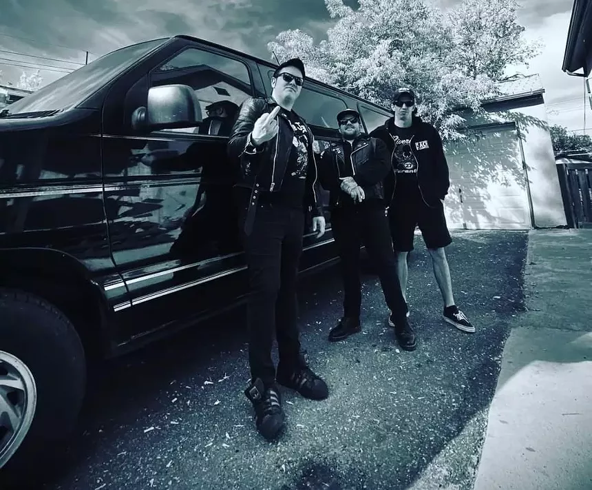 three men in black stand outside  a van
