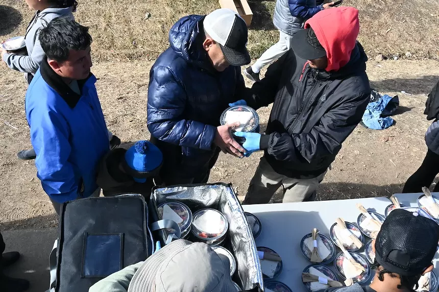 Migrants pick up a lunch.