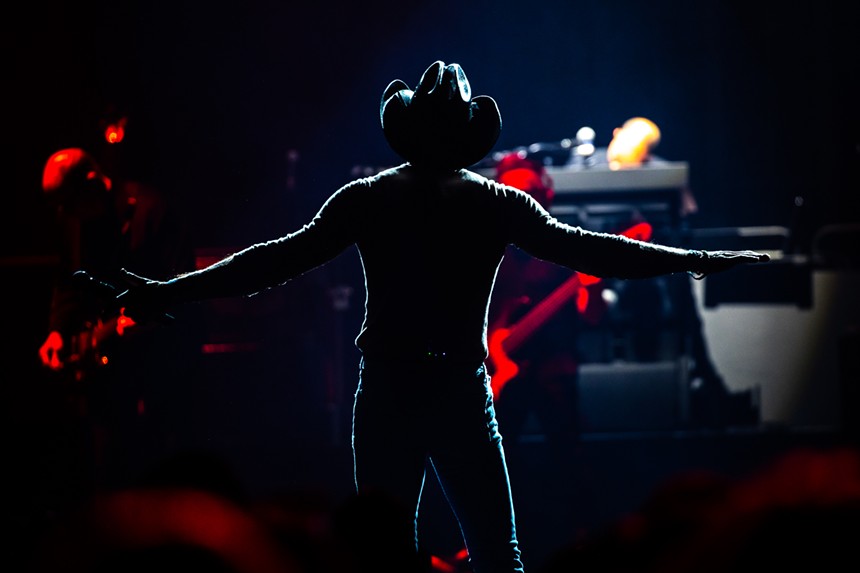 silhouette of a man in a cowboy hat with his arms stretched out