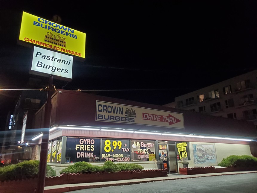 outside of a drive-thru burger restaurant with yellow sign at night