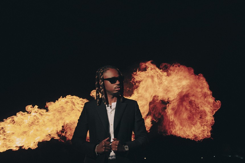 man in a suit standing in front of flames