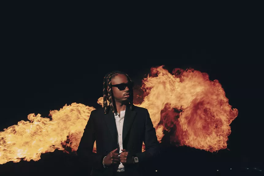 man in a suit standing in front of flames