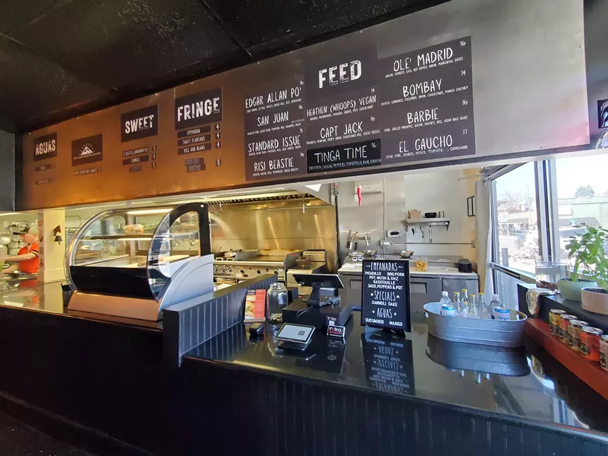 menu board hanging over a counter inside a fast-casual restaurant