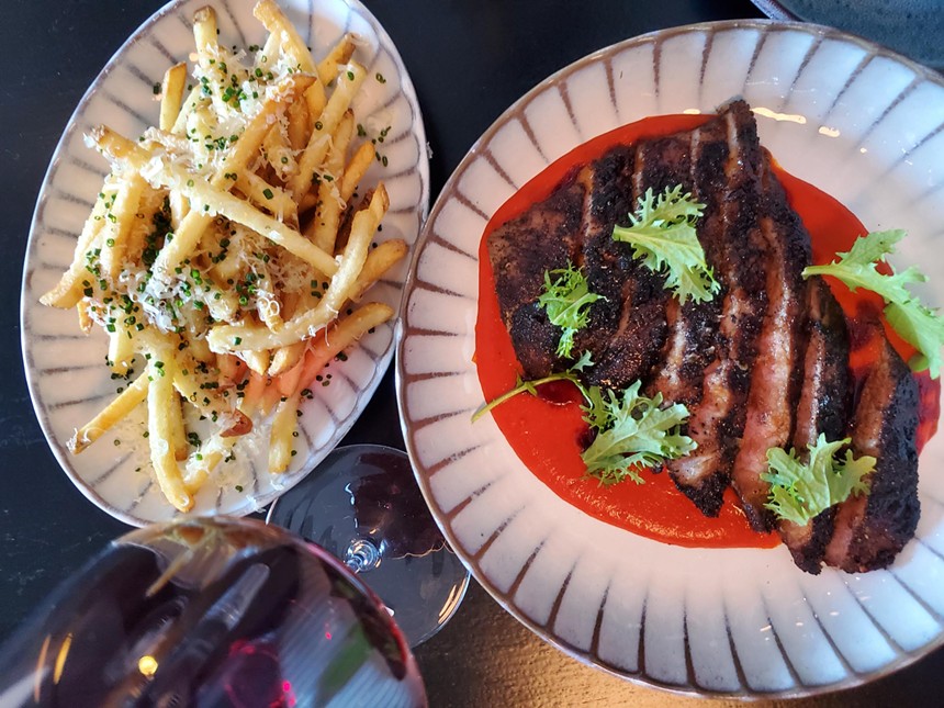 french fries on a plate next to sliced pork over a red sauce